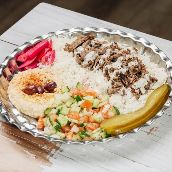 MidEast Eats' shawarma plate with rice, hummus, salad, pickled turnips, and a pickle.