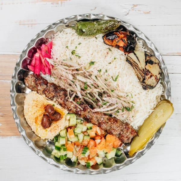 MidEast Eats' Middle Eastern platter with kebab, rice, hummus, salad, and grilled vegetables.